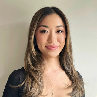 Hayley Fung smiling with layered brown hair, wispy lashes, and glossy pink lips.