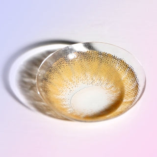 Macro shot of a brown blended colored contact lens, showing the dotted pattern designed to enhance naturally dark eyes, on a light background