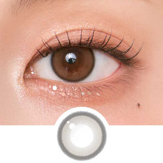 Close-up shot of model's eye adorned with Chuu Aery Rose Lucid Brown (10pk) daily color contact lenses with prescription, complemented by glittery eye makeup, showing the brightening and enlarging effect of the circle contact lens on dark brown eyes, above a cutout of the contact lens pattern with limbal ring on a white background.