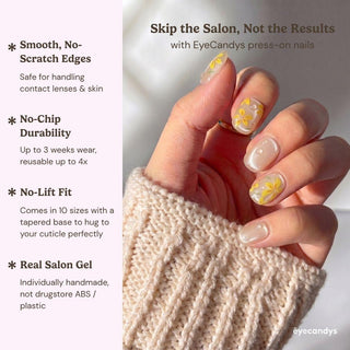 A hand with long, handmade After Rain Press-On Nails by EyeCandys in yellow daisy design holds a mug. The person wears a cream sweater. Text highlights salon gel look, smooth edges, and no-chip durability—reusable and easy to apply.