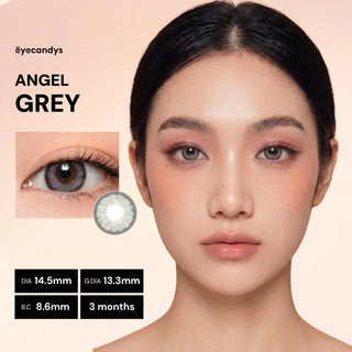 A woman with smooth skin wears EyeCandys Pink Label Angel Grey color contacts. An inset shows a close-up of her eye with the lenses. Text lists: "PINK LABEL ANGEL GREY," DIA 14.5mm, G.DIA 13.3mm, B.C 8.6mm, 3 months, EyeCandys logo.