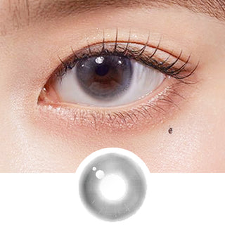 Close-up shot of model's eye adorned with Chuu Aube Pie Moon Grey (10pk) daily color contact lenses with prescription, complemented by clean eye makeup, showing the brightening and enlarging effect of the circle contact lens on dark brown eyes, above a cutout of the contact lens pattern with limbal ring on a white background.