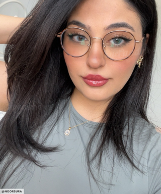 Model wearing Glossy Blue colour contact lenses with winged eyeliner, under a pair of prescription round glasses