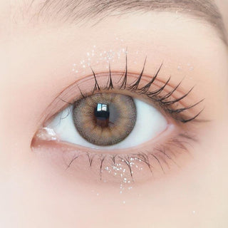 Close-up of model's eye wearing with Ann365 Buttercup 1-Day Beige (10pk) Korean color contact lens with prescription, complemented with barely there eye makeup, showing the brightening and enlarging effect of the circle lens on dark brown eyes.