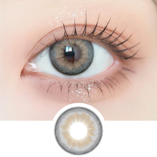 Close-up shot of model's eye adorned with Ann365 Buttercup 1-Day Grey (10pk) daily color contact lenses with prescription, paired with clean-girl eye makeup, showing the brightening and enlarging effect of the circle contact lens on dark brown eyes, above a cutout of the contact lens with limbal ring on a white background.
