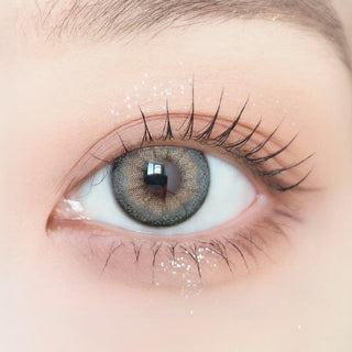 Close-up of model's eye wearing with Ann365 Buttercup 1-Day Grey (10pk) Korean color contact lens with prescription, complemented with barely there eye makeup, showing the brightening and enlarging effect of the circle lens on dark brown eyes.