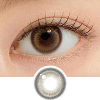 Close-up shot of model's eye adorned with Chuu Lily Daze Sun Brown daily color contact lenses with prescription, complemented by clean eye makeup, showing the brightening and enlarging effect of the circle contact lens on dark brown eyes, above a cutout of the contact lens pattern with limbal ring on a white background.
