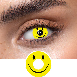 Yellow smiley face contact lenses on an dark eye, showing the opacity and vividness of the Halloween contact lens, above a cutout of the yellow contact lens pattern