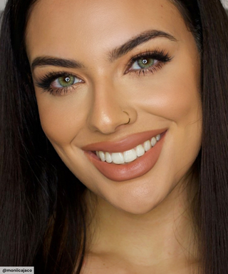 Smiling model wearing Desire Sandy Beige prescription colour contacts paired with peach eyeshadow and long eyelashes