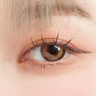 Close-up shot of model's eye adorned with Eyesm Dollring Anne Brown prescription colored contacts, complemented by clean eye makeup, showing the brightening effect of the prescription cosmetic contact lens on dark brown eyes.