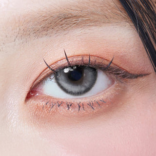 Close-up shot of model's eye adorned with Eyesm Dollring Jamie Grey prescription colored contacts, complemented by clean eye makeup, showing the brightening effect of the prescription cosmetic contact lens on dark brown eyes.