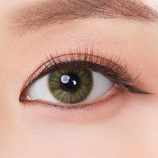 Macro shot of an eye wearing the Olola Heiress Olive (KR) prescription colour contact lens, showing the multi-colored detail and natural effect on dark brown eyes.