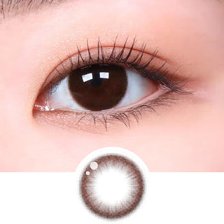 Close-up shot of model's eye adorned with Ann365 JUST Choco (Toric for Astigmatism) (1 PAIR) daily color contact lenses with prescription, paired with clean-girl eye makeup, showing the brightening and enlarging effect of the circle contact lens on dark brown eyes, above a cutout of the contact lens with limbal ring on a white background.