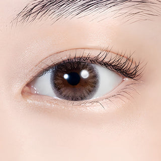 Close-up of an eye wearing Lilmoon Monthly Flamingo prescription and non-prescription colored contact lenses. Soft pink and sheer gray circle lenses with a two-tone gradient create a glossy, romantic eye look while naturally enhancing dark brown eyes. Monthly Japanese colored contacts with a delicate blush undertone, smoky halo, natural enlargement effect, and comfortable everyday wear.