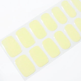 Angled image of semi-cured gel nail stickers in the design 'Melon Magic,' featuring a gradient of light baby colors mainly yellow with iridescent effect, perfect for a stylish manicure.