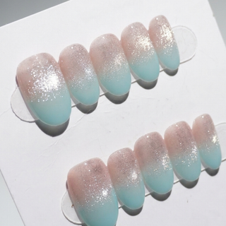 EyeCandys Mist n Fade Press-On Nails feature a handmade gradient design, blending soft pink at the cuticle into light blue tips, topped with glitter for salon-quality shine and a gel-like finish.