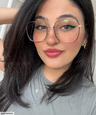 Model with black hair and natural simple make up look wearing Mystic Oversized Square vintage-inspired prescription eyeglasses, available in blue light blocking lenses and in readers with magnification, from EyeCandys. Pictured is the Green Tea (army-green) color.