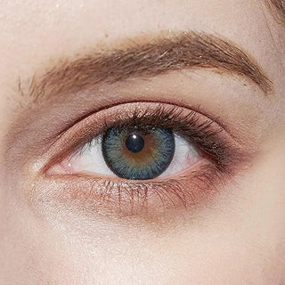 Close-up of a light-skinned eye with bushy eyebrow, subtle eyelid makeup, and striking NEO Vision Cosmo Blue coloured contact lenses by NEO Vision.
