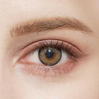 A close-up of a human eye with fair skin and natural makeup wearing NEO Vision Cosmo Grey lenses by NEO Vision, highlighting the subtle effect of these coloured contacts alongside groomed eyebrows and light brown-green eye tones.