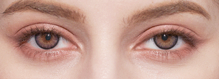 Close-up of a person's face highlighting both eyes with green irises enhanced by NEO Vision Cosmo Green contact lenses from NEO Vision, featuring natural makeup, neatly groomed eyebrows, and smooth skin.