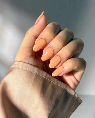 Hand wearing EyeCandys Tangerine Cream Gel Nail Sticker – soft pastel orange manicure inspired by creamy citrus tones. Sweet, playful, and perfect for spring and summer. Vegan, non-toxic gel nail stickers with salon-quality shine.