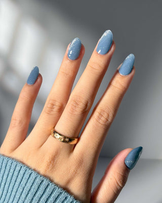 Hand featuring EyeCandys Denim Sugar Gel Nail Stickers in blue with glitter details. Effortless spring nails that last 2-3 weeks, with a 7-free, allergy-friendly formula. Cures in sunlight in just 5-10 minutes, delivering a stylish, sparkling look without a UV lamp.