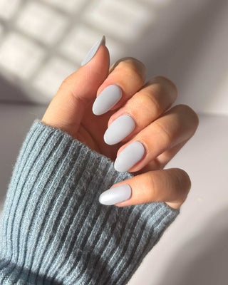 Hand showcasing EyeCandys Blueberry Milk Gel Nail Stickers in a soft pastel blue. Effortless spring nails with a 7-free, allergy-friendly formula that lasts 2-3 weeks. Cures in sunlight, no UV lamp needed, for a chic and long-lasting manicure.