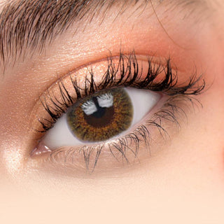 Close up view of model wearing Pink Label New York Brown contact lens on a contrasting surface