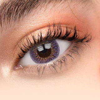Close-up of Pink Label New York Violet contact lens in a model's eye showing off peach eyeshadow on her naturally dark eyes