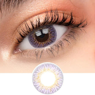 Close-up view of Pink Label New York Violet contact lens lens on a pristine white surface model has dark brown eye, paired with natural eye makeup, next to a cutout of the contact lens