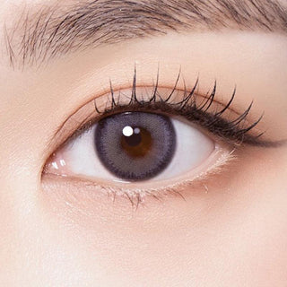 Macro shot of an eye wearing the Olola Muted Grey prescription colour contact lens, showing the multi-colored detail and natural effect on dark brown eyes.