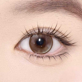 Olala Meow Savannah Brown color contact lens on top of a dark eye paired with subtle eye makeup and curled wispy eyelashes