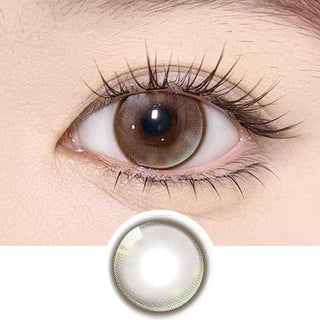 Olala Meow Savannah Brown color contact lens on top of a dark eye paired with subtle eye makeup and curled wispy eyelashes, above the contact lens design.