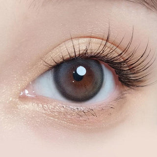 Macro shot of an eye wearing the Olola Blurring Grey prescription colour contact lens, showing the multi-colored detail and natural effect on dark brown eyes.