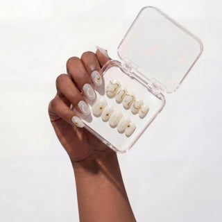 Hand wearing reusable Gilt Lines press on nails featuring sculpted white texture and metallic gold accents for a clean, modern luxury manicure.