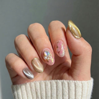 Hand wearing EyeCandys Champagne Problems press on nails featuring champagne and grey cat eye shimmer, blush base, pearl cluster, and crystal accents.