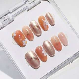 Eyecandys Short oval press on nails Peachy Keen with sheer jelly base, white daisy nail art, gold foil flakes, rose gold metallic nail, and mauve shimmer accent.