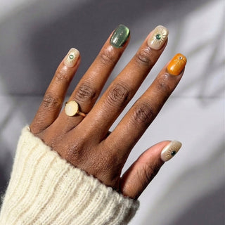 Hand wearing EyeCandys Sun Spell summer press on nails with artistic sun details and cat-eye finish.