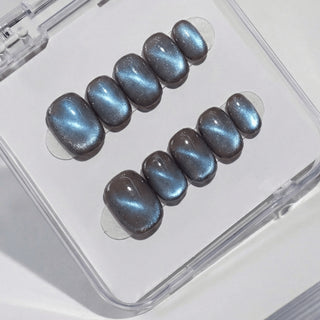 Close-up of EyeCandys Midnight Cocoa press on nails featuring deep chocolate brown cat-eye base with cool blue-grey shimmer on a white background.