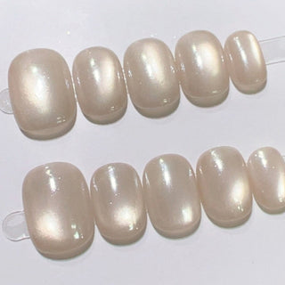 Close-up of EyeCandys Moon Syrup press on nails on a white background featuring semi-sheer jelly nude base with pearly cat-eye glow and glossy natural finish.