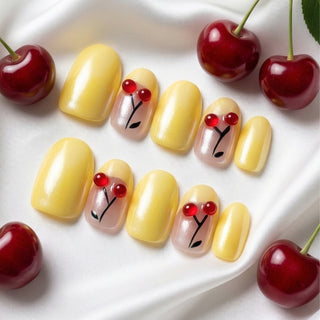 Close-up of EyeCandys Cherry Picnic press on nails on a white background featuring pastel yellow base with chrome finish, French tips, and sculpted cherry accents.
