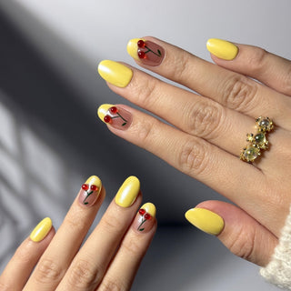 Hand wearing EyeCandys Cherry Picnic press on nails with pastel yellow chrome base, French tips, and sculpted cherry accents.