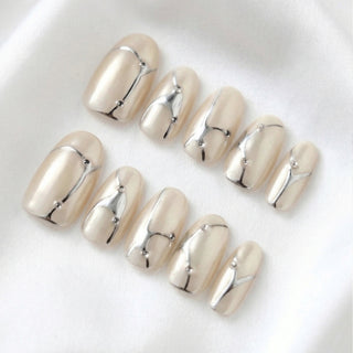 Close-up of EyeCandys In the Lines press on nails featuring soft white cat-eye base with pearly shimmer, delicate silver line details, and subtle gem accents on a white background.