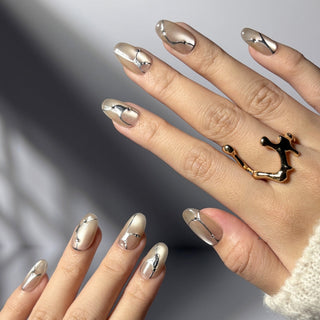 Hand wearing EyeCandys In the Lines press on nails with soft white cat-eye base, pearly glow, silver vein lines, and small gem accents.