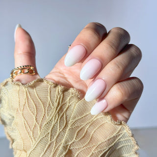 Hand showcasing EyeCandys Peach Latte Gel Nail Stickers featuring a white and peach ombre design. Achieve a trendy, long-lasting spring manicure with a 7-free, allergy-friendly formula. Lasts 2-3 weeks, no UV lamp needed for curing in sunlight.