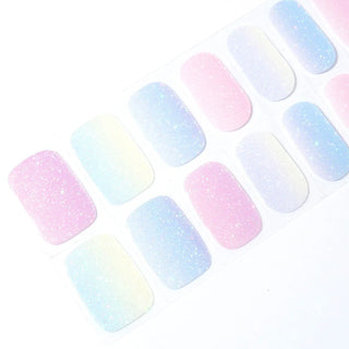 Angled image of semi-cured gel nail stickers in the design 'Pearl Skittles,' showcasing a glittery pastel gradient with hues of pink, blue, and yellow for a playful and elegant look.
