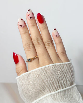 Close-up of hand wearing EyeCandys Petite Cherry semi-cured gel nail stickers in a vibrant red and cherry-inspired polka dot design. A fun, fruity nail look perfect for spring, offering a glossy, long-lasting manicure with easy at-home application.