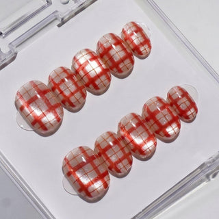 Picnic Date Press-On Nails by EyeCandys feature a glossy white base with a red plaid pattern, neatly arranged in two rows inside a clear plastic boxโperfect for achieving a salon-quality gel manicure at home.
