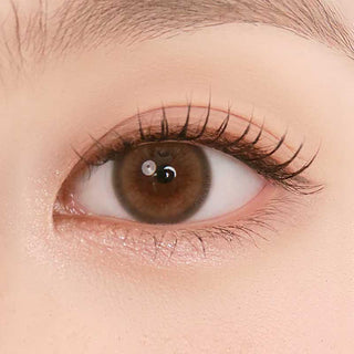 Close-up shot of model's eye adorned with Chuu Pompon Pop Bubble Brown (10pk)daily color contact lenses with prescription, complemented by natural eye makeup, showing the brightening and enlarging effect of the circle contact lens on dark brown eyes.