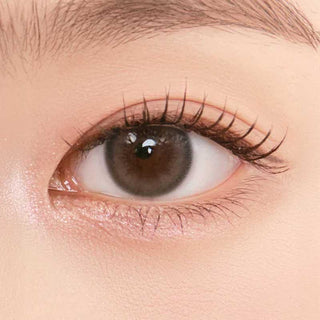 Close-up shot of model's eye adorned with Chuu Pompon Pop Bubble Grey (10pk)daily color contact lenses with prescription, complemented by natural eye makeup, showing the brightening and enlarging effect of the circle contact lens on dark brown eyes.